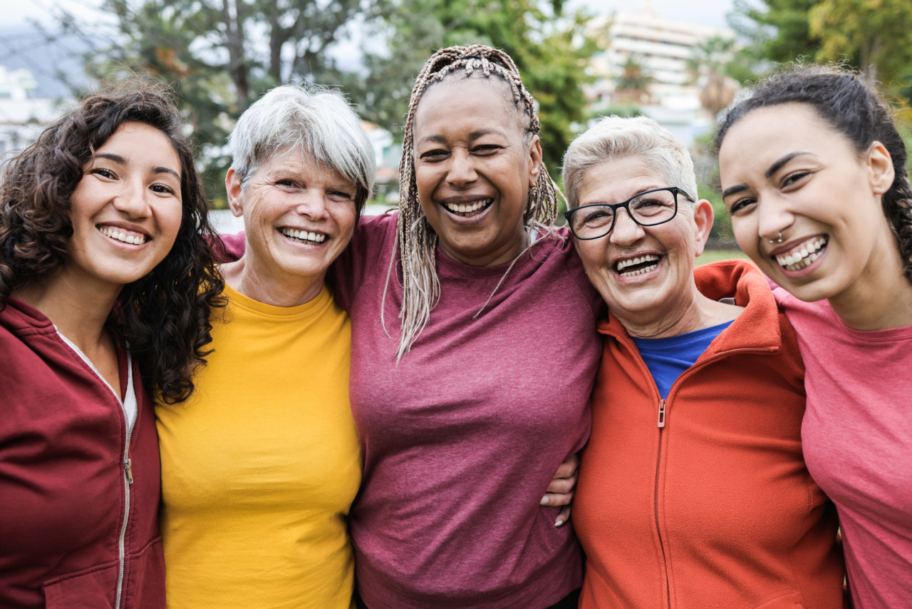 A group of women of various ages with their arms around each other, smiling